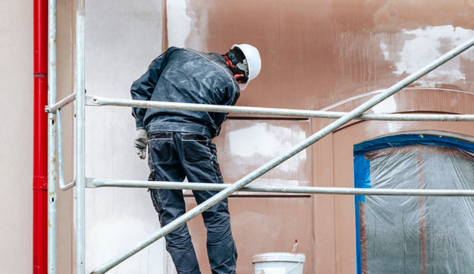 Professional worker painting exterior of a building