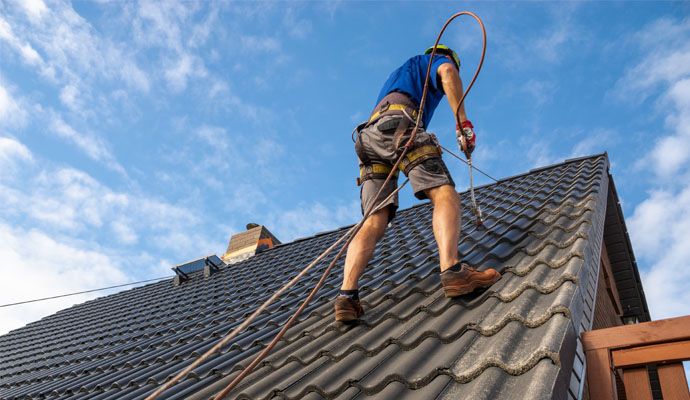 Person applying paint on roof