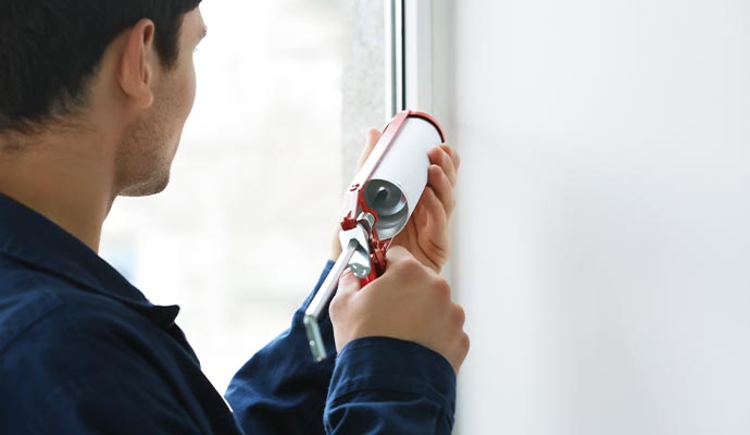 Person sealing wall crack with equipment