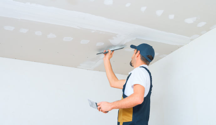 A professional repainting a repaired drywall